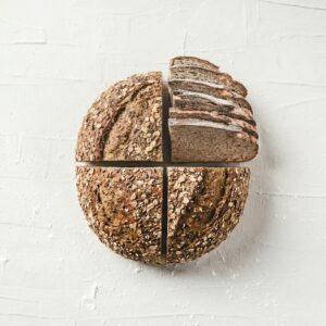 Seeded multigrain sourdough loaf coated in whole seeds on a rustic wooden board, sliced to show a dense hearty crumb